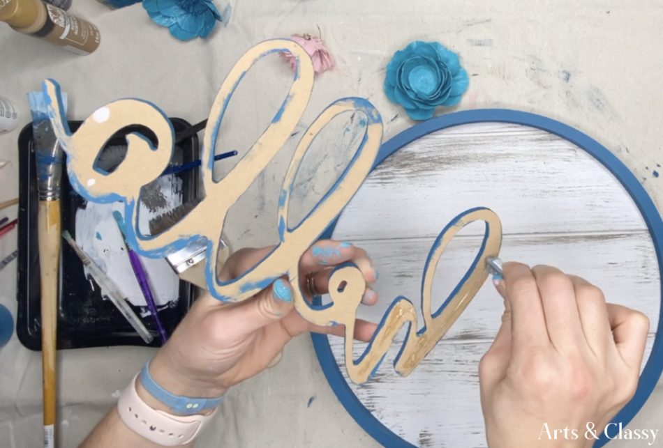 Once my craft hoop was firmly applied to the wood round and the glue had dried, I did the same gluing to the hello wood sign cutout. 