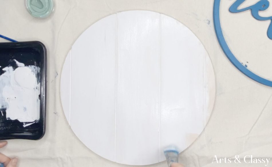I began painting the wood trim and the wood round. I chose a beautiful blue color from my trim and wanted a nice stark contrast with a white background on my wood round. This wood round had a pallet wood look to them so giving it a white wash with paint really helped give it some rustic charm. 