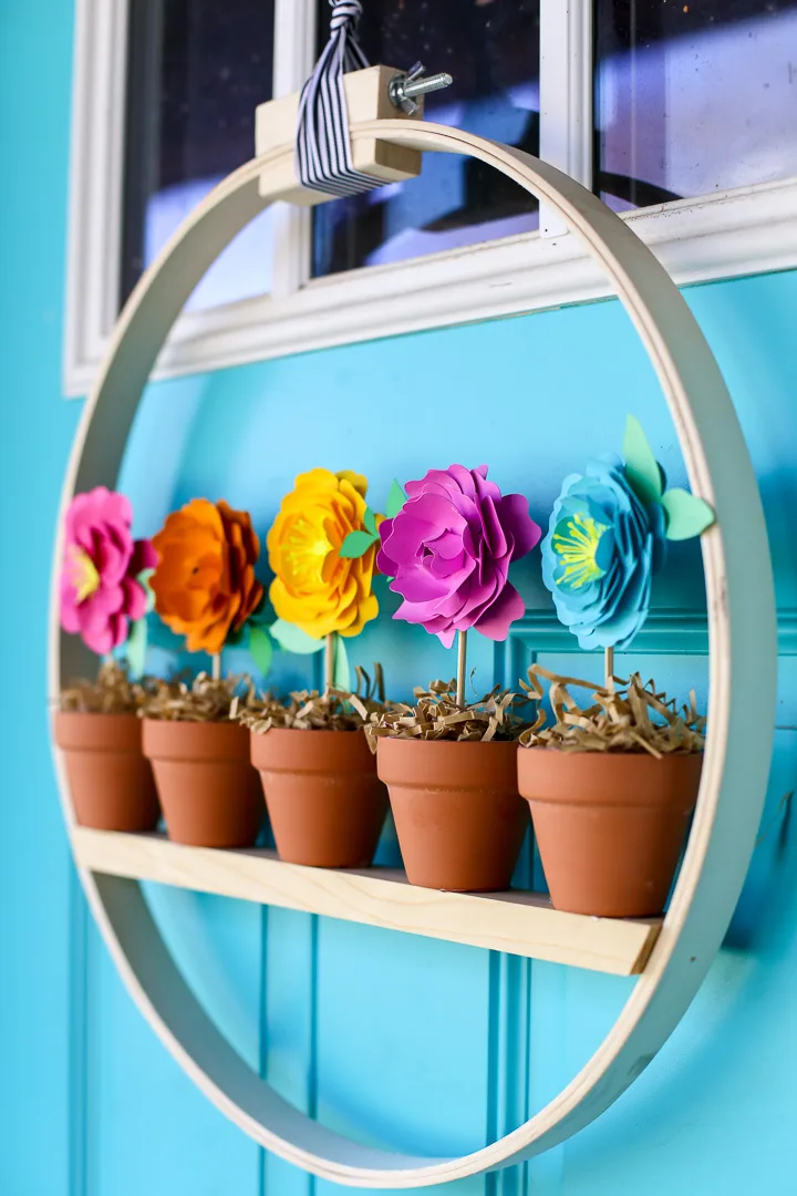 This spring, try incorporating flower pots and pot decor into your DIY front door decorations. Utilize a wreath hanger to hang two or three matching potted plants. Stand out from the crowd with some DIY wreath hanger door decorations. Challenge the traditional norms by changing out wreaths and add flower pots for a pop of color. 