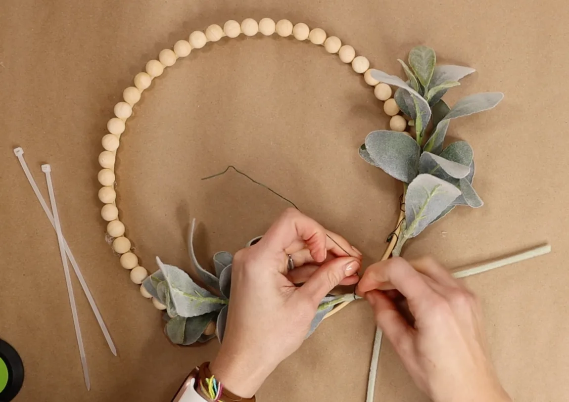 The first layer of greenery that I chose was lambs' ear. You can get 2 steps for $2 at Walmart! What a great deal! Position the greenery in the way you want it to be displayed and attach it with floral wire and a clear zip tie. Use hot glue if needed for additional support on the hoop.