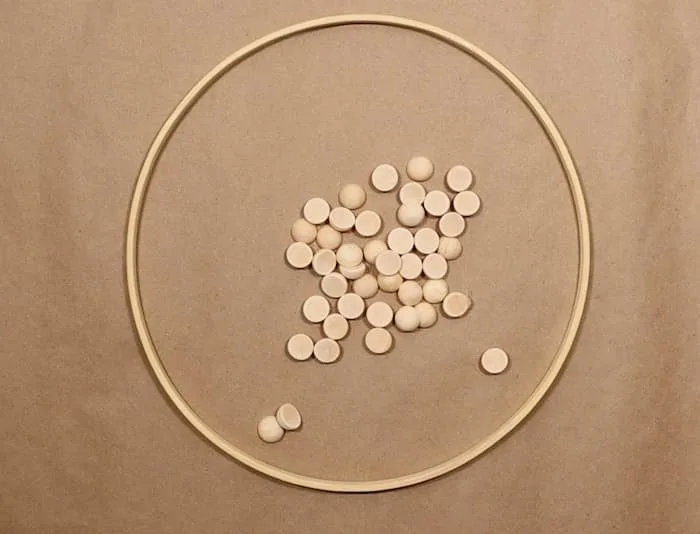Using a wreath form of wood craft hoop to provide a sturdy base, I grabbed some 15mm wood bead slices close by and set to work using the hot glue gun. 